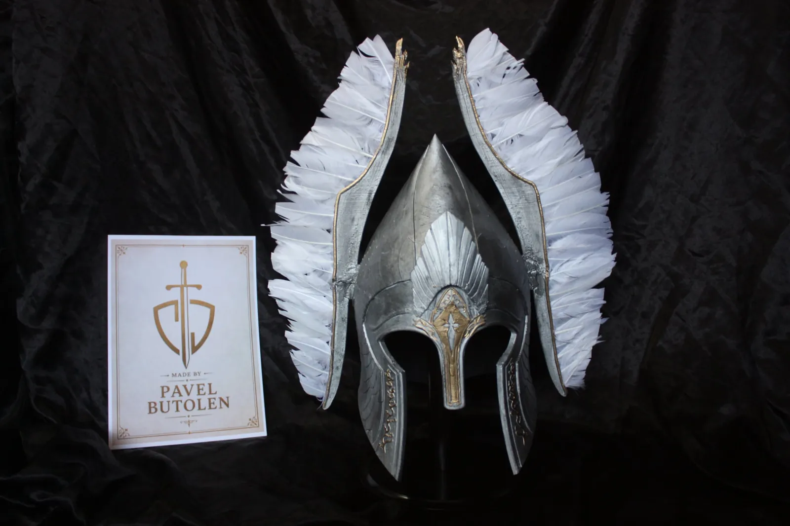 Srebrna kaciga s bijelim krilima i karticom Pavel Butolen