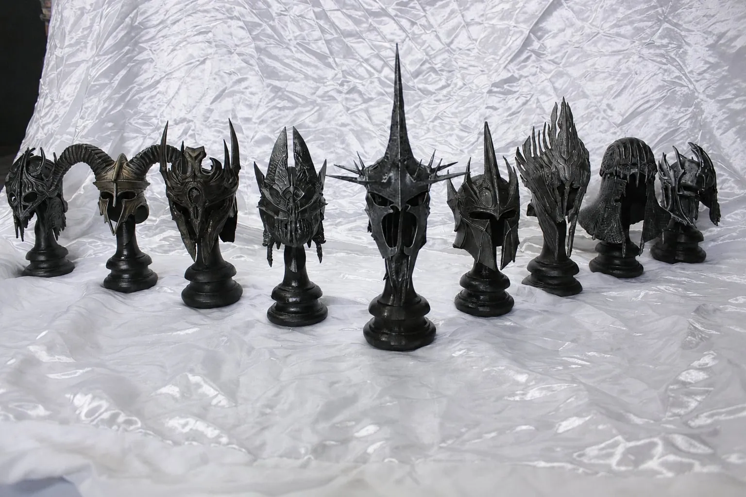 Niz tamnih fantasy kaciga na crnim postoljima